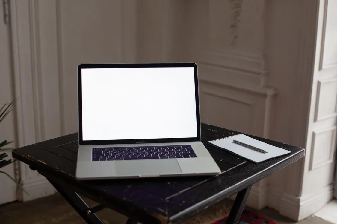 Computador portátil, caderno e caneta num espaço de avaliação profissional